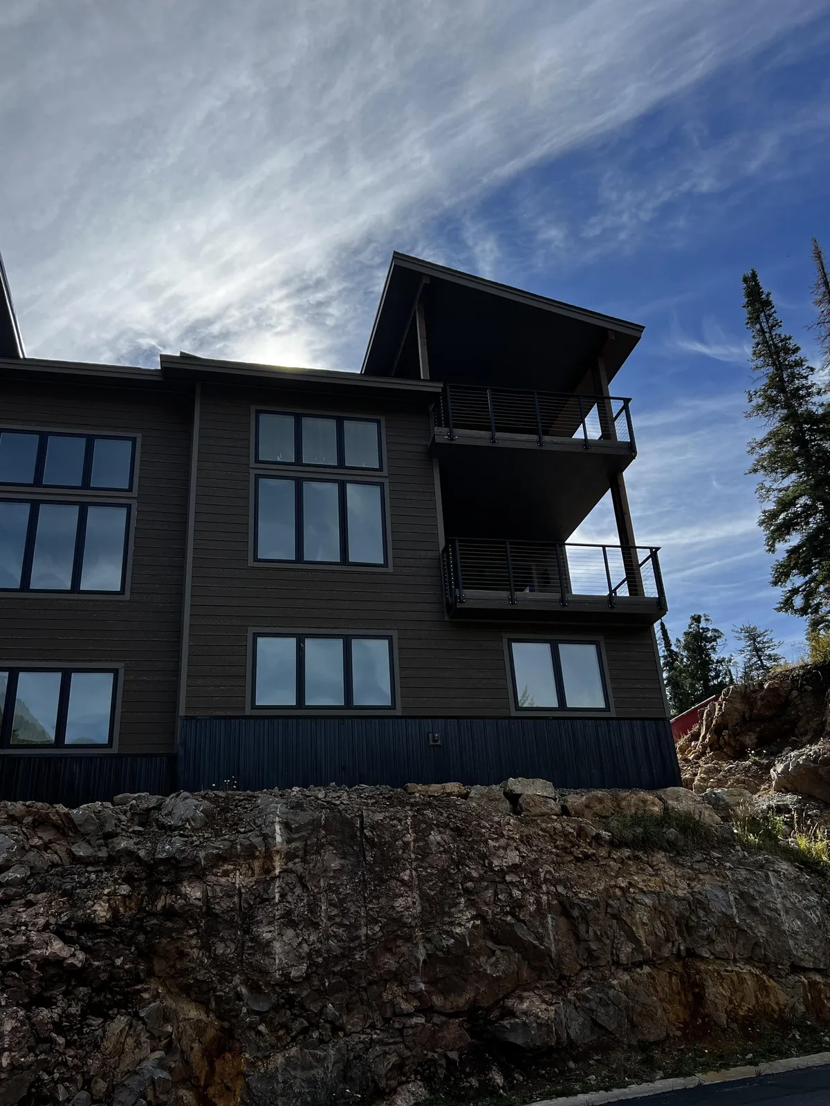 A contemporary exterior view of the townhome, showcasing its modern architecture with large windows and a balcony. The backdrop hints at the surrounding natural landscape, inviting guests to imagine relaxing outdoors or setting off for adventure right from their doorstep.