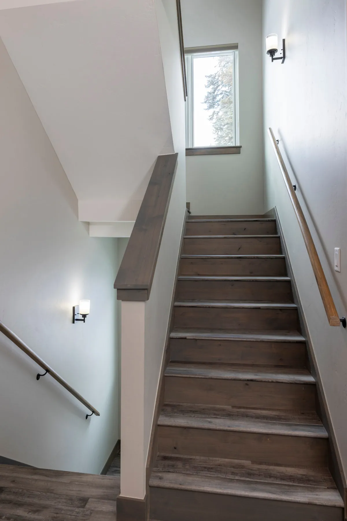 A bright, welcoming staircase area inside the home, with a window allowing natural light to pour in and views toward the outside. The space suggests connectivity between levels and offers a sense of movement and transition from indoors to out.