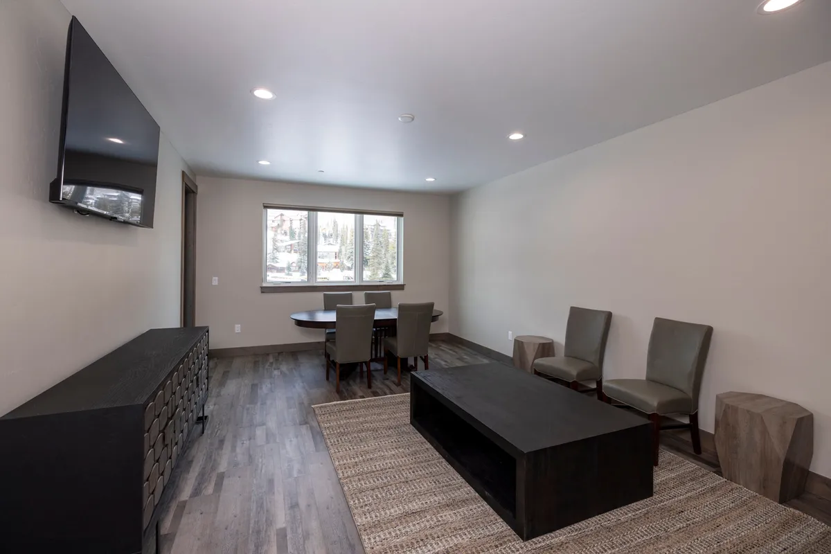An inviting interior dining space is shown, featuring a stylish table and seating area by a large window that opens up to a scenic view. The setup encourages communal meals, celebrations, and relaxed conversations while staying connected to the outdoors.